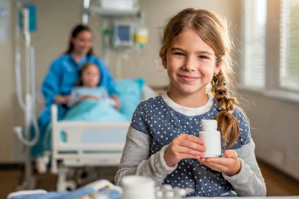 Ein lächelndes Mädchen bekommt im Spitalzimmer ein Medikament